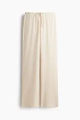 Pantalón de punto fino color beige, de corte relajado con piernas rectas y cintura elástica con cordón ajustable.