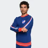 Buzo de cuello redondo color azul, con detalles en rojo y blanco en cuello, puños y ruedo. Presenta el escudo del Club Nacional de Football en el pecho y bandas laterales con diseño deportivo en las mangas.
