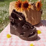 Sandalia de cuero marrón con plataforma y taco cuña de madera, tiras cruzadas en el empeine y tira ajustable con hebilla en el tobillo.