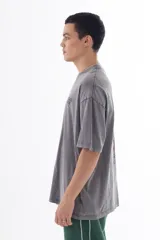 Remera gris con efecto acid wash, corte oversize y estampa en la espalda con personajes de dibujos animados (Bob Esponja, Itchy, Peppa Pig y Bart Simpson) con fajos de billetes.