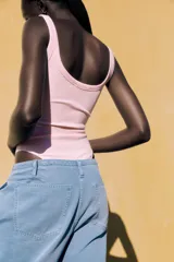 Body negro de escote redondo y tirantes anchos. Cierre inferior con botones a presión. Tejido de punto acanalado.