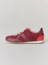Championes de cuero en tonos bordó y rojo, con diseño de paneles combinados en gamuza y cuero texturizado. Presentan suela blanca con base dentada color caramelo y cordones jaspeados.