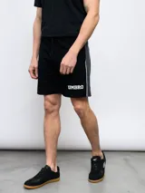 Bermuda deportiva Umbro negra de piqué, con cordón ajustable en la cintura, logo estampado en blanco y detalle de piping gris en los laterales.