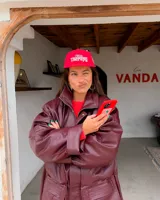 Gorra de béisbol de cinco paneles sin estructura color rojo, con visera plana y bordado frontal en tono crudo con la frase 'I NEED Therapy'. Presenta detalles bordados adicionales y correa ajustable de nailon en la parte trasera.
