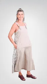 Vestido midi de lino y algodón color beige, de corte amplio y silueta acampanada, con tirantes anchos ajustables mediante botones, bolsillos laterales appliqués y paneles laterales con diseño de rayas.