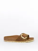 Sandalias tipo slide modelo Madrid Big Buckle de Birkenstock, color cognac. Presentan una correa ancha de cuero nubuck engrasado con una hebilla metálica dorada de gran tamaño. Cuentan con una plantilla anatómica de corcho y látex forrada en cuero napa y suela de EVA.