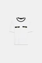 Camiseta negra de manga corta y corte slim fit, con cuello redondo ribeteado en blanco y dos bolsillos de plastrón en el pecho con un botón dorado cada uno.