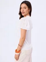 Remera blanca con cuello redondo y mangas cortas abullonadas con detalle de bordado suizo.