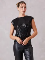 Blusa de lentejuelas color negro, con cuello a la base, sin mangas y detalle de nudo en el ruedo.