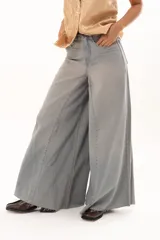 Pantalón de jean tiro alto con diseño de pierna extra ancha y caída fluida. Presenta costuras verticales que realzan su estructura, bolsillos funcionales y terminación de ruedo deshilachado.