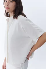 Camisa manga corta color crudo con cuello camisero y cierre frontal de botones, confeccionada con mezcla de lino.