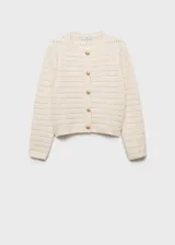 Chaqueta de punto calado en color crema, con cuello redondo, manga larga y cierre frontal mediante botones dorados. Presenta un diseño recto y tejido de punto medio.