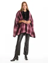 Ruana de tejido suave, color beige y marrón con estampado geométrico repetitivo. Posee cuello con aplique de piel sintética marrón y ribetes negros. Se combina con un suéter marrón de manga larga con botones en el puño.