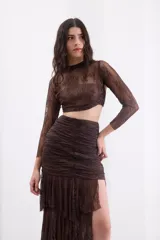 Falda larga de encaje color negro, de silueta ajustada con volados escalonados y abertura lateral pronunciada.