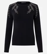 Suéter de punto en color negro con cuello redondo y mangas largas. Presenta un delicado bordado floral con pedrería en la zona de los hombros.