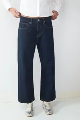 Jeans de tiro medio con corte barrel y ajuste relajado, diseño clásico de cinco bolsillos, cierre frontal de cremallera y botón metálico.