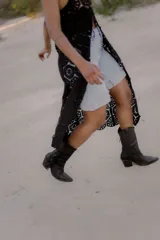 Bota texana de caña media color marrón, confeccionada en cuero gamuzado, con punta marcada, taco de 6 cm y flecos laterales.