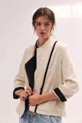 Chaqueta de lino lavado color blanco, con cuello mao, cierre metálico diagonal y detalles en contratono.