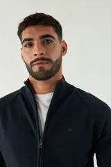 Campera tejida color verde militar, con cuello alto, puños y logo bordado.