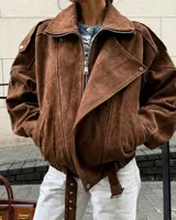 Campera de gamuza color marrón, con diseño tipo bomber de corte oversize. Presenta cierre frontal, cuello solapa, hombreras con detalle de broche y ruedo con elástico y cinturón incorporado.
