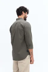 Camisa de gabardina azul marino con efecto stone wash, doble bolsillo frontal con solapa y botón, y fit regular.
