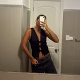 Chaleco negro con escote en V profundo y cierre frontal mediante lazos ajustables.