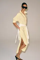 Vestido midi camisero de algodón, color amarillo con estampado a cuadros. Cuenta con cuello solapa, escote en V, mangas cortas con puño y bolsillos laterales ocultos en la costura, con diseño evasé.