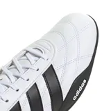 Championes Adidas Groundpulse de perfil bajo, inspirados en el automovilismo. Presentan un exterior blanco con las tres tiras características en negro, costuras decorativas acolchadas y suela de caucho negra con diseño envolvente en el talón.