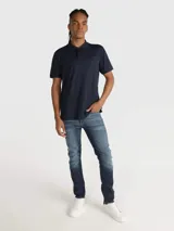 Chomba de piqué azul marino con cuello clásico, tapeta de dos botones y logo tonal de Calvin Klein bordado en el pecho. Corte clásico y mangas cortas.