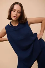 Top sin mangas de punto acanalado color amarillo, con cuello redondo y terminaciones festoneadas en piquitos. Presenta botones decorativos en forma de florcitas en la parte delantera.