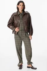 Chaqueta de cuero sintético con textura granulada, corte oversize, cuello camisero, cierre frontal con botones a presión, bolsillos frontales tipo cargo y detalles de charreteras en los hombros.