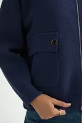Abrigo de punto negro con cuello alto y cierre frontal completo. Presenta un diseño de corte recto con bolsillos frontales y terminaciones en tejido acanalado.