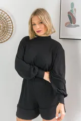 Conjunto de dos piezas en color crema, compuesto por un buzo de cuello alto, mangas largas abullonadas y ajuste en la cintura, junto con un short de tiro alto con terminaciones al corte.