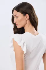 Remera de algodón color beige, de manga corta con volados de broderie, escote redondo y cuerpo liso.