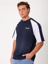 Remera holgada Rusty modelo Isel, de diseño bicolor con cuerpo azul marino y mangas ranglán blancas. Cuenta con cuello redondo ribeteado y pequeño logo bordado en el pecho.