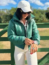 Campera puffer corta de color verde, con cuello alto, cierre frontal y puños elásticos. Diseño acolchado con acabado brillante.