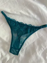 Bombacha tipo tanga de encaje color verde petróleo, con diseño floral y tiras laterales ajustables.