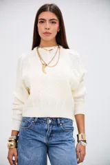 Sweater de punto con diseño de trenzas, color crudo, de cuello redondo y manga larga con puños acanalados.