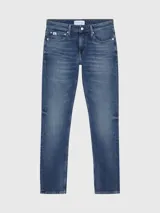 Jeans de hombre, talle bajo, corte slim ajustado, confeccionados en denim azul medio vintage con efecto desgastado. Presentan bragueta con cremallera y diseño de cinco bolsillos.