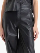 Pantalón Frey de cuero ovino color negro, con frunces en el puño de la botamanga que aportan volumen. Tiene cintura doble con pespunte y botones forrados en cuero.