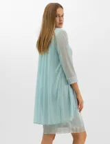 Conjunto de dos piezas compuesto por un vestido corto de silueta recta en tejido plisado metalizado con escote redondo adornado con pedrería y perlas, y una chaqueta de gasa liviana con frente abierto, caída en cascada y mangas tres cuartos con puños metalizados.