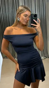 Vestido corto de lurex color azul marino con escote strapless, diseño ajustado con frunces laterales y falda con volado asimétrico.