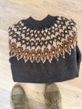 Sweater tejido a mano de corte clásico, color gris con diseño de guarda nórdica en el canesú en tonos blanco, marrón y detalles en rojo.