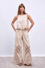 Blusa color beige con bordados de palmeras y conchas marinas en color marrón.