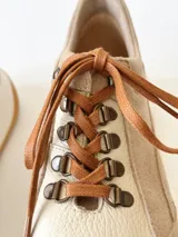 Championes de cuero color visón con cordones marrones, suela blanca y base color caramelo.