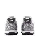 Championes urbanos New Balance modelo 204, color gris con detalles en blanco y negro. Confeccionados en malla técnica y refuerzos sintéticos, presentan el logo lateral característico de la marca y suela de goma con relieve.