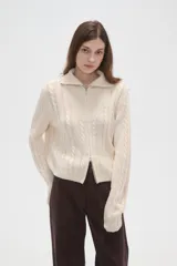 Saco de punto de algodón con diseño de trenzas, cuello alto y cierre frontal completo. Presenta un corte al cuerpo y mangas largas.