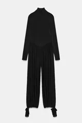 Mono largo negro con cuello subido y manga larga ajustada. El cuerpo superior es liso y ajustado, mientras que la parte inferior es de pantalón ancho con mucho volumen y frunces, ajustado en el tobillo con una lazada.