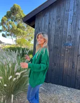 Buzo verde de lana y poliamida, con diseño oversize, cuello redondo y trenzas en la parte delantera.