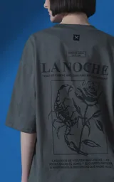 Remera de manga corta con cuello redondo y calce oversize, color gris oscuro. Presenta una estampa frontal con diseño gráfico de un escorpión y una rosa, junto con texto tipográfico.